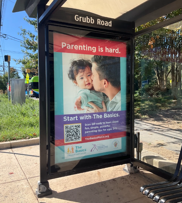 Photo of a large ad for The Basics at a bus stop on Grubb Road with the headline "Parenting is Hard. Start with The Basics."